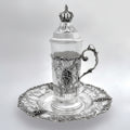 Silver teacup with lid and decorative elements on a white background