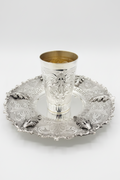 Silver kiddush cup with intricate design on a matching tray
