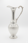 Silver pitcher with textured design on a white background