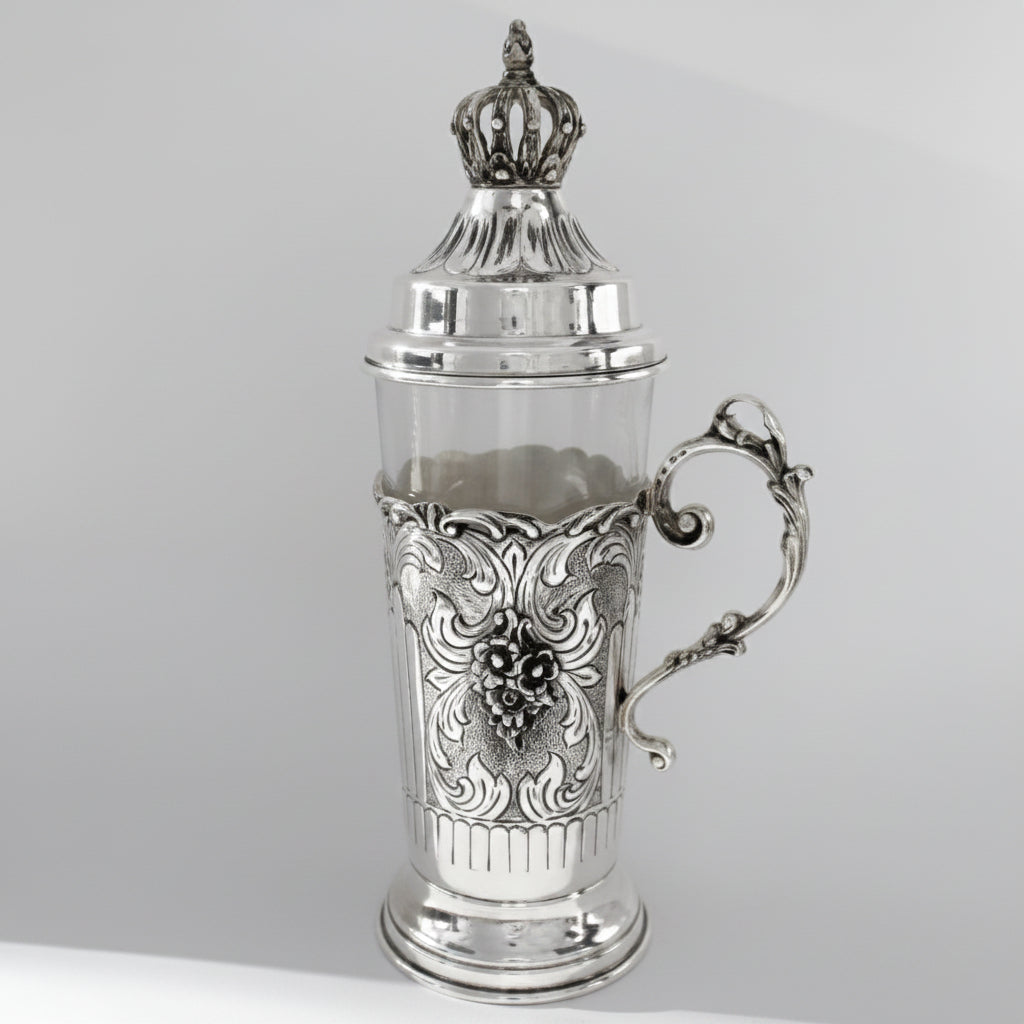 Silver teacup with intricate designs on a gray background