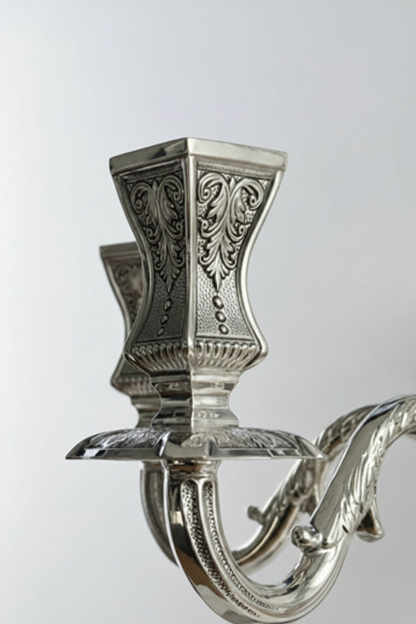 Silver candle holder with intricate designs on a white background