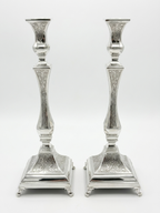 Pair of silver candlesticks with intricate engravings on a white background