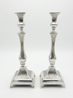 Pair of silver candlesticks with intricate designs on a white background