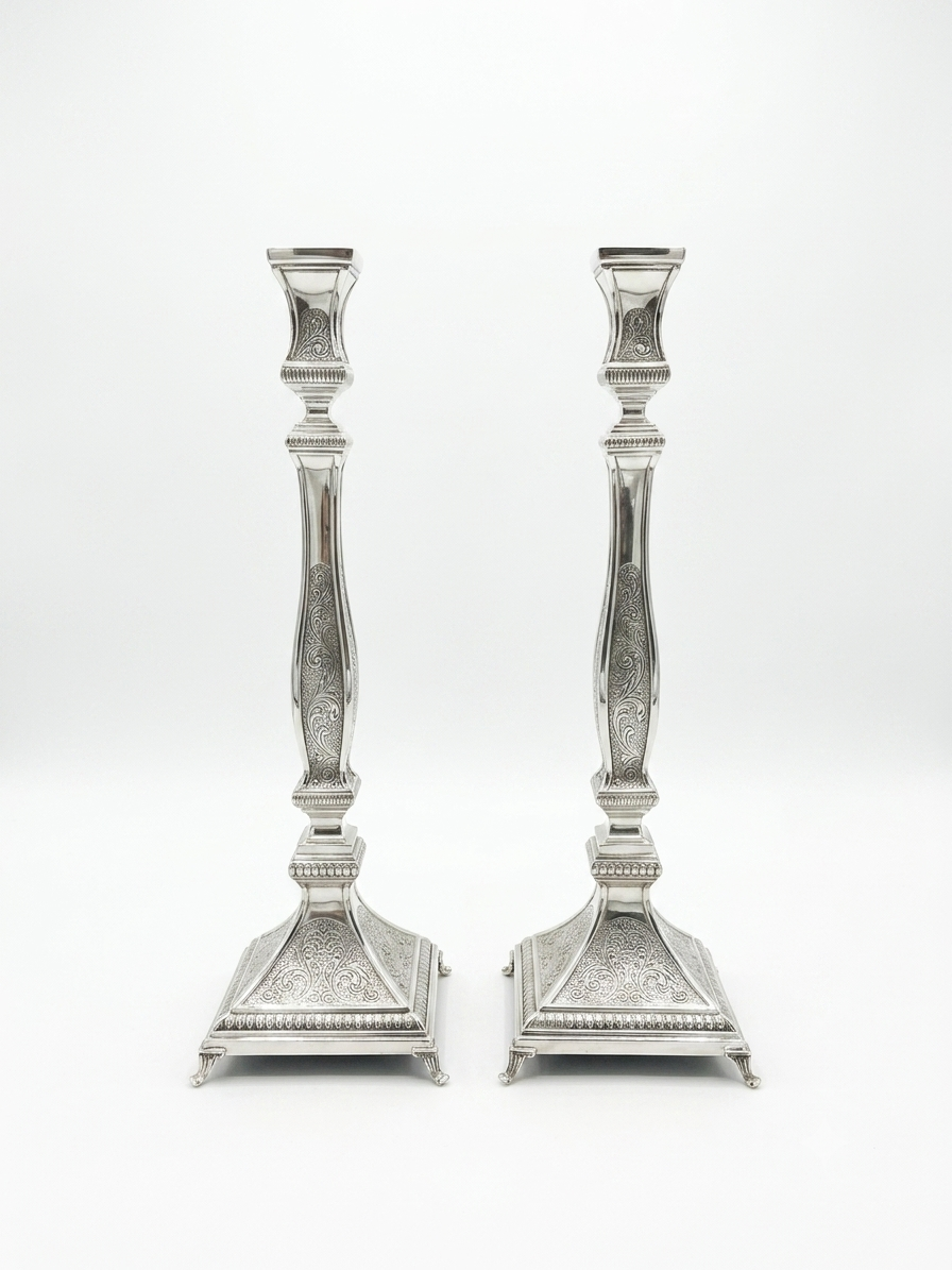 Pair of silver candlesticks with intricate designs on a white background by hadad bros