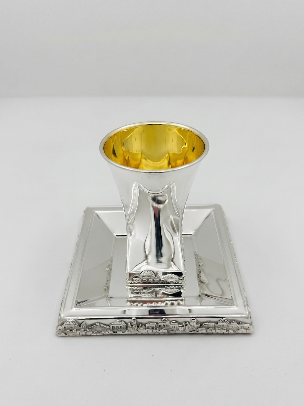 Hadad bros A silver Kiddush cup with a gold interior, set on a matching square silver tray with a decorative Jerusalem cityscape border