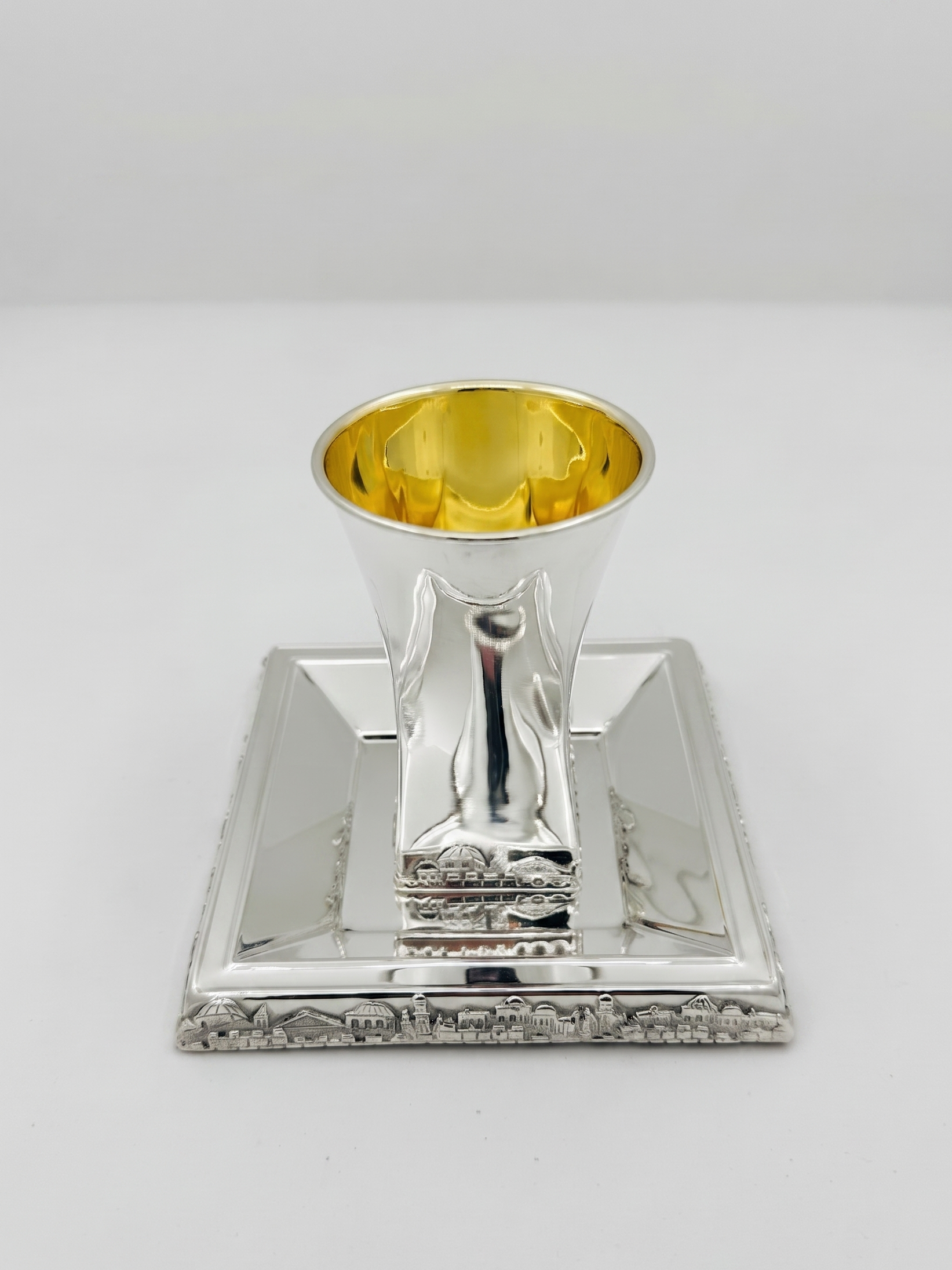 Hadad bros A silver Kiddush cup with a gold interior, set on a matching square silver tray with a decorative Jerusalem cityscape border