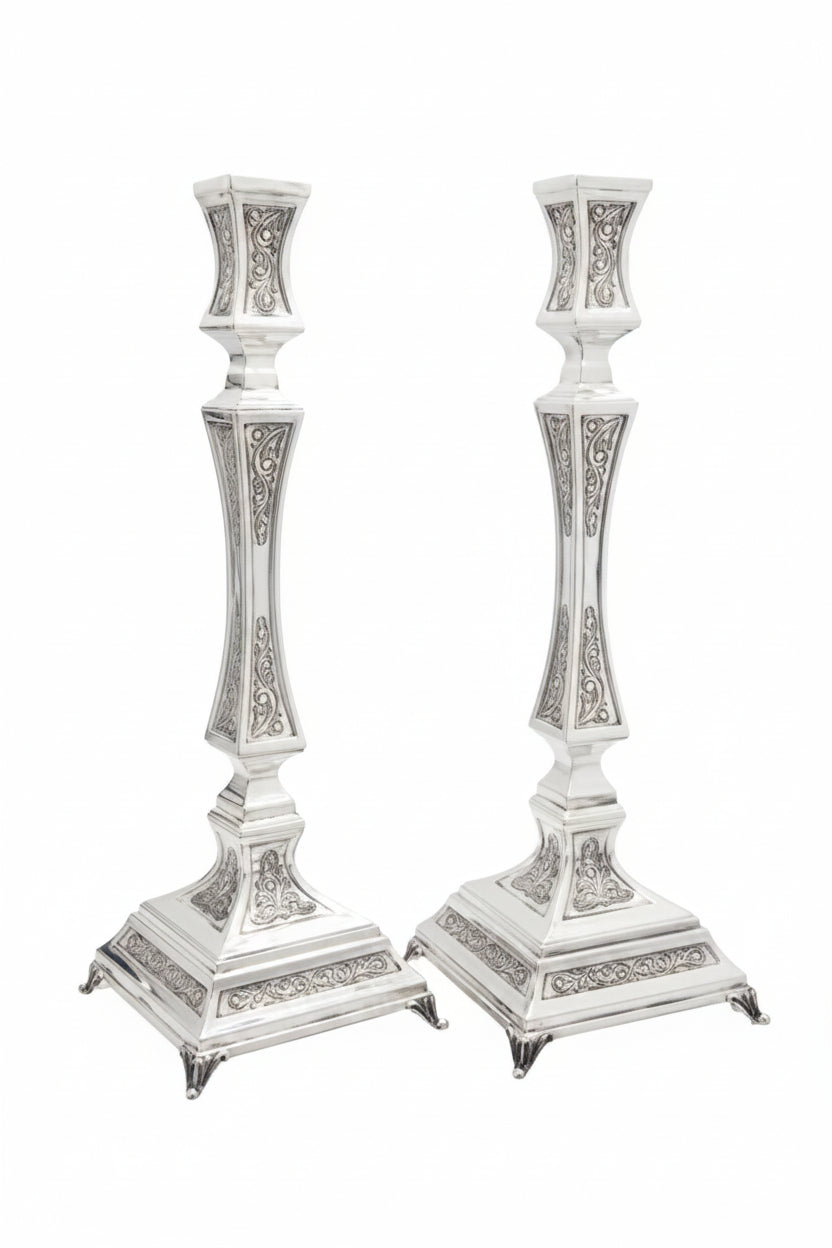Two silver candlesticks with intricate designs on a white background