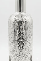 Silver bottle with intricate engravings on a white background