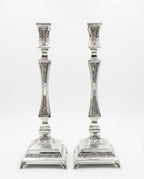 pair of Silver candlesticks with intricate designs on a white background