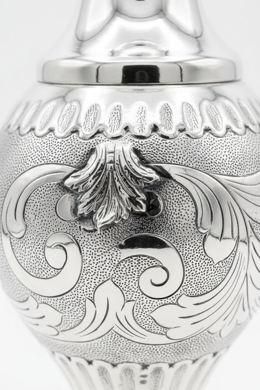 Silver decorative bottle with intricate designs on a white background