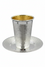 Silver and gold kiddush cup with matching saucer on a white background
