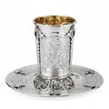 Silver kiddush cup with gold interior on a matching tray against a white background